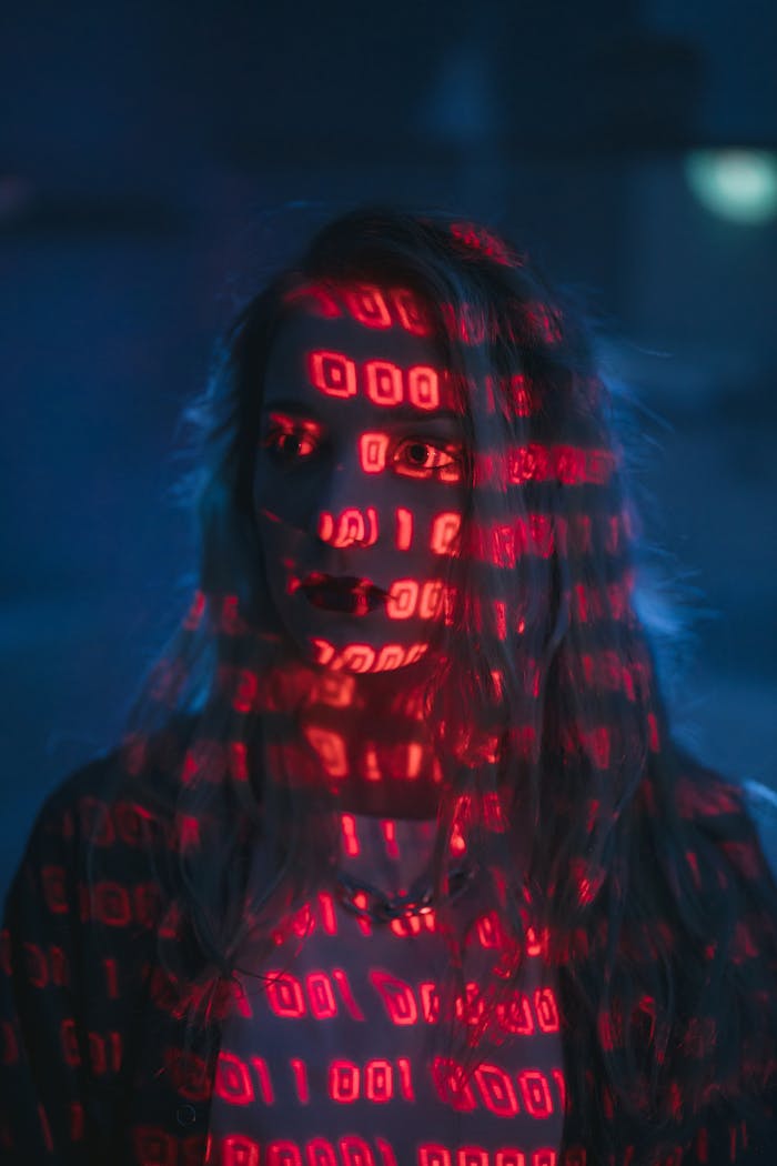 The Art of Drawing Readers In: Your attractive post title goes here A woman with red binary code projected on her face, signifying technology and cybersecurity.